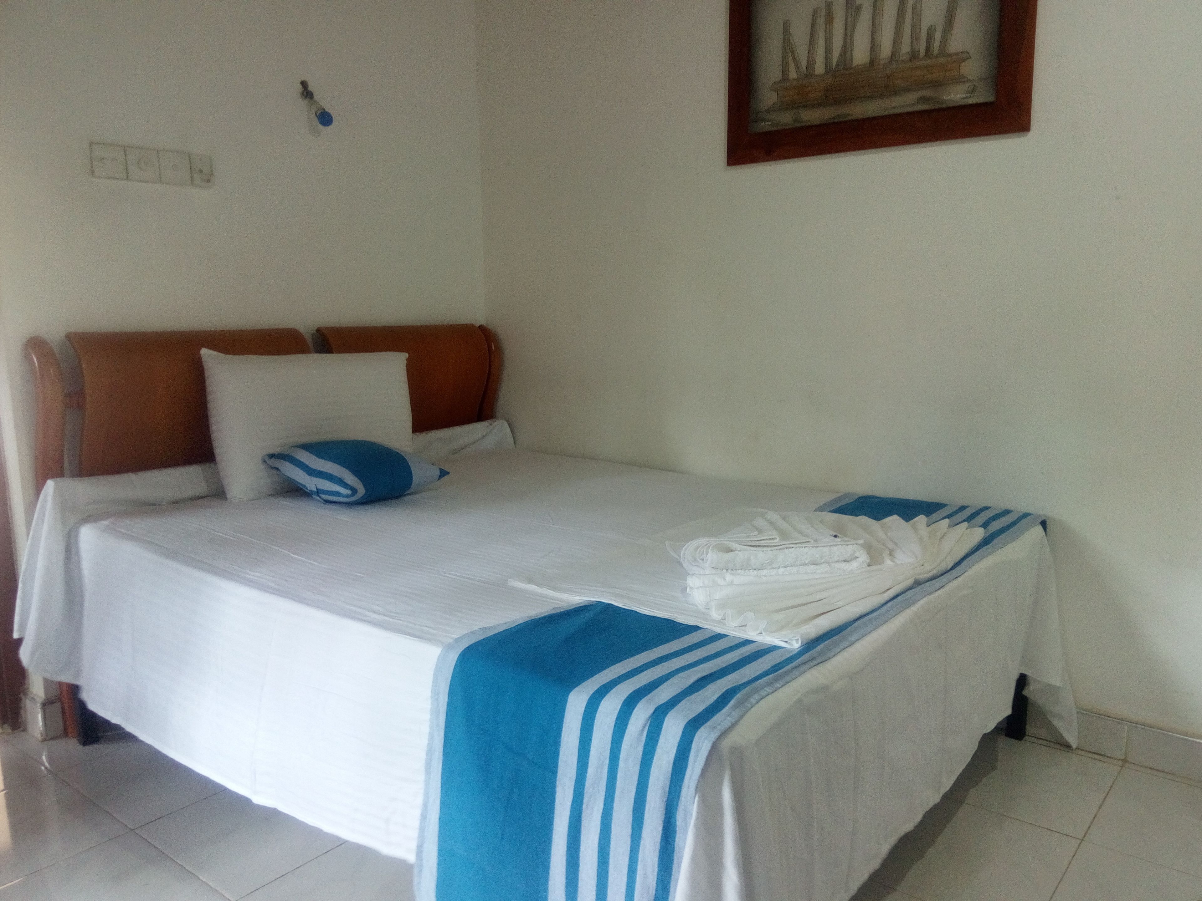 A neatly made bed with white and blue striped bedding, a folded towel, and a pillow.