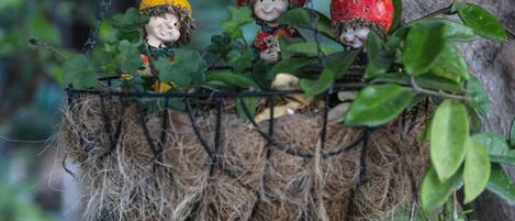A decorative hanging with three figurines, each wearing a hat and holding a fruit.