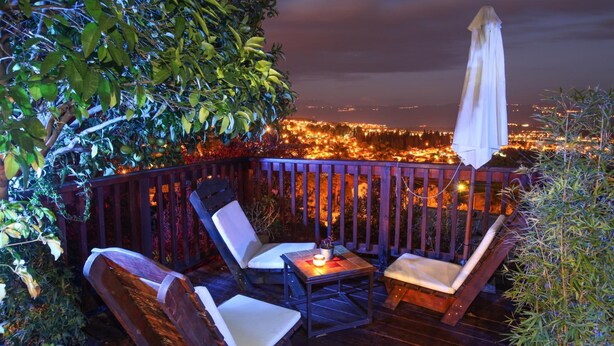 A deck with two chairs and a table, overlooking a cityscape at night. - Havaya Ba Nof (Rosh Pinna)