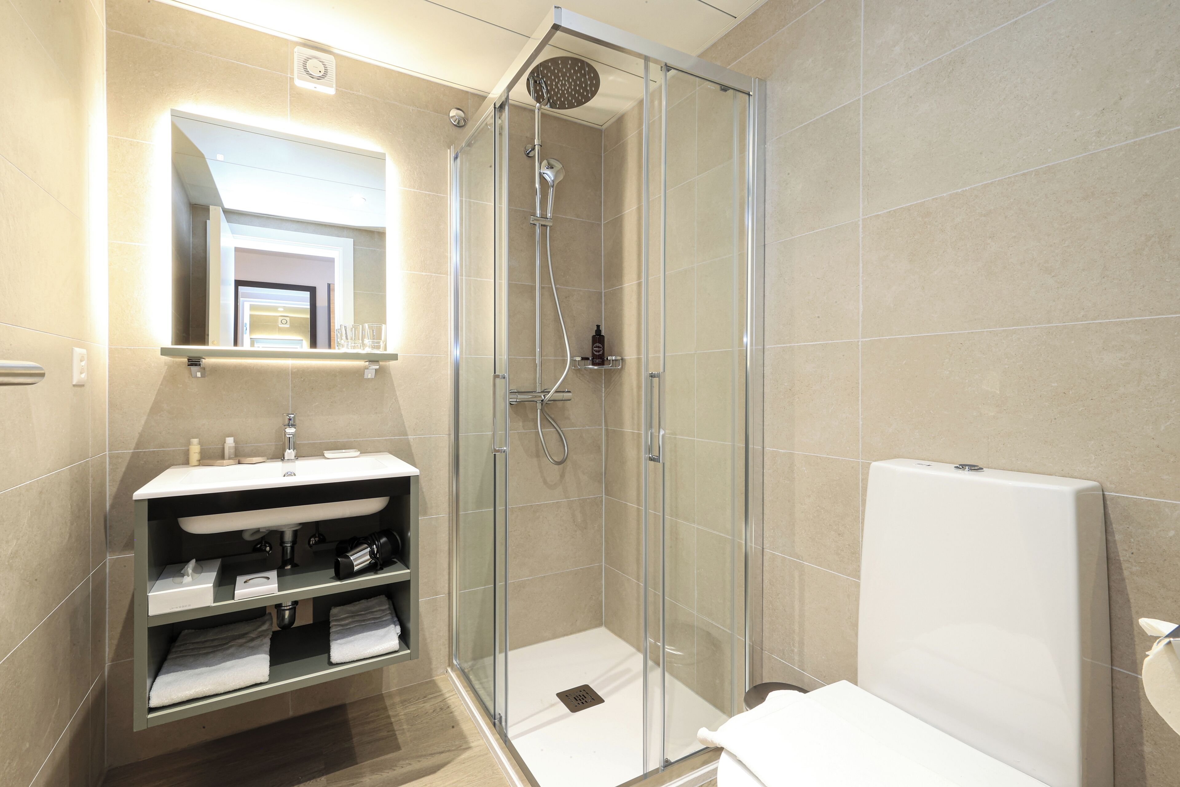 A modern bathroom with a glass-enclosed shower, a white sink, and a mirror above the vanity.