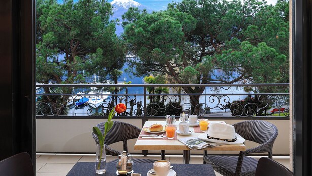 Comedor con mesas dispuestas para el desayuno, con vista a un paisaje que incluye árboles y un cuerpo de agua.