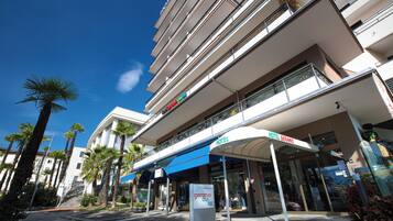 A hotel with a modern design, featuring a prominent entrance with a blue awning and a sign that reads "Hotel Geranio."