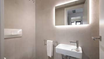 Un baño moderno con un lavamanos blanco, un perchero y un espejo.