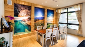 A dining area with wooden walls, a large window with curtains, and a table with chairs. - Fun Going B&B (Hualien City)