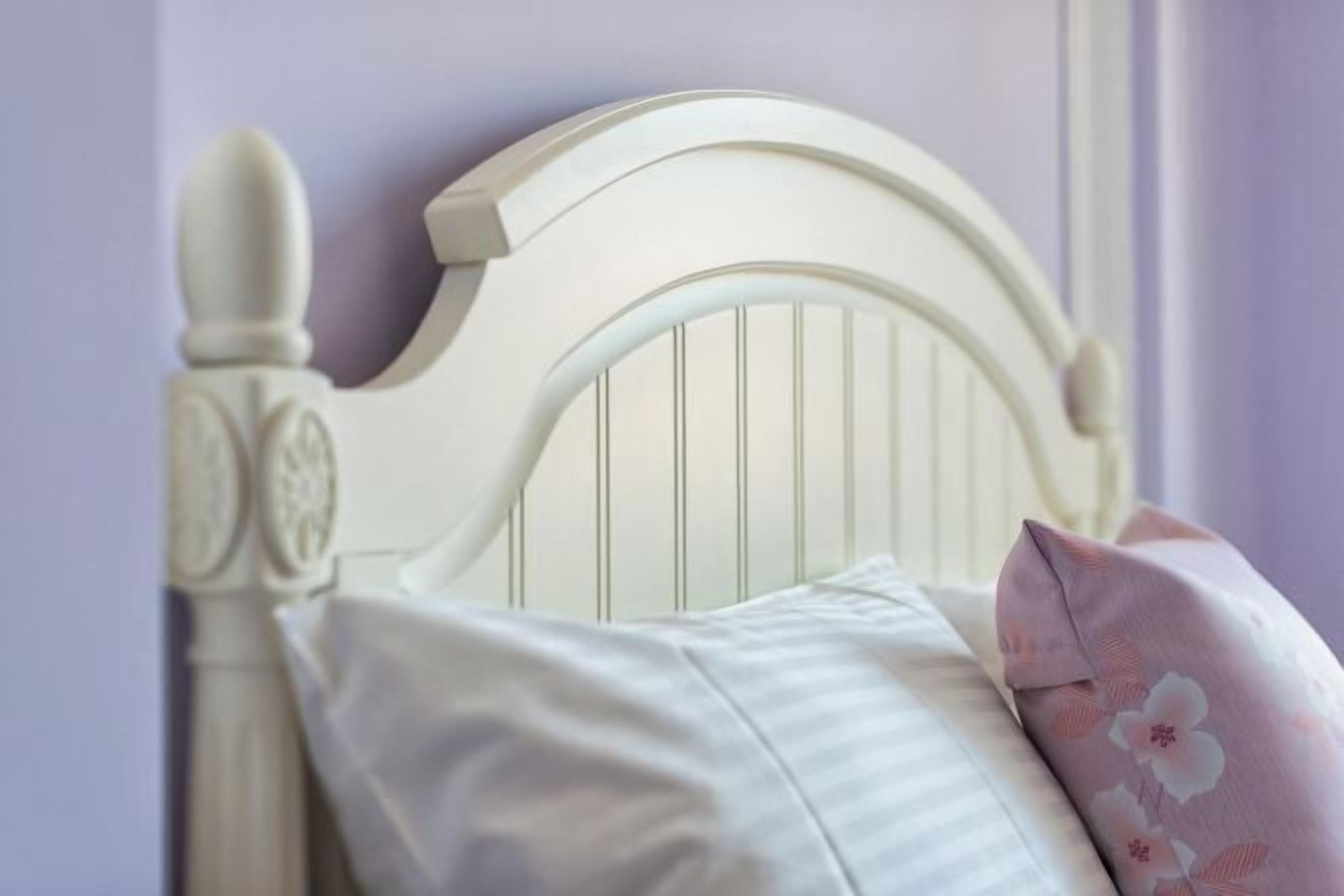 A white headboard with vertical slats and a decorative finial.