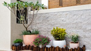 A landscaped outdoor area with various potted plants and a wooden fence. - Fun Going B&B (Hualien City)