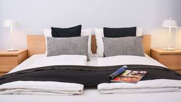 A neatly made bed with a magazine and glasses on it, two nightstands with lamps, and a wooden headboard.