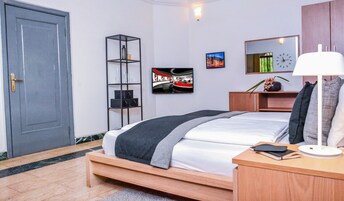 A modern bedroom with a bed, bedside table, lamp, shelf, and artwork.