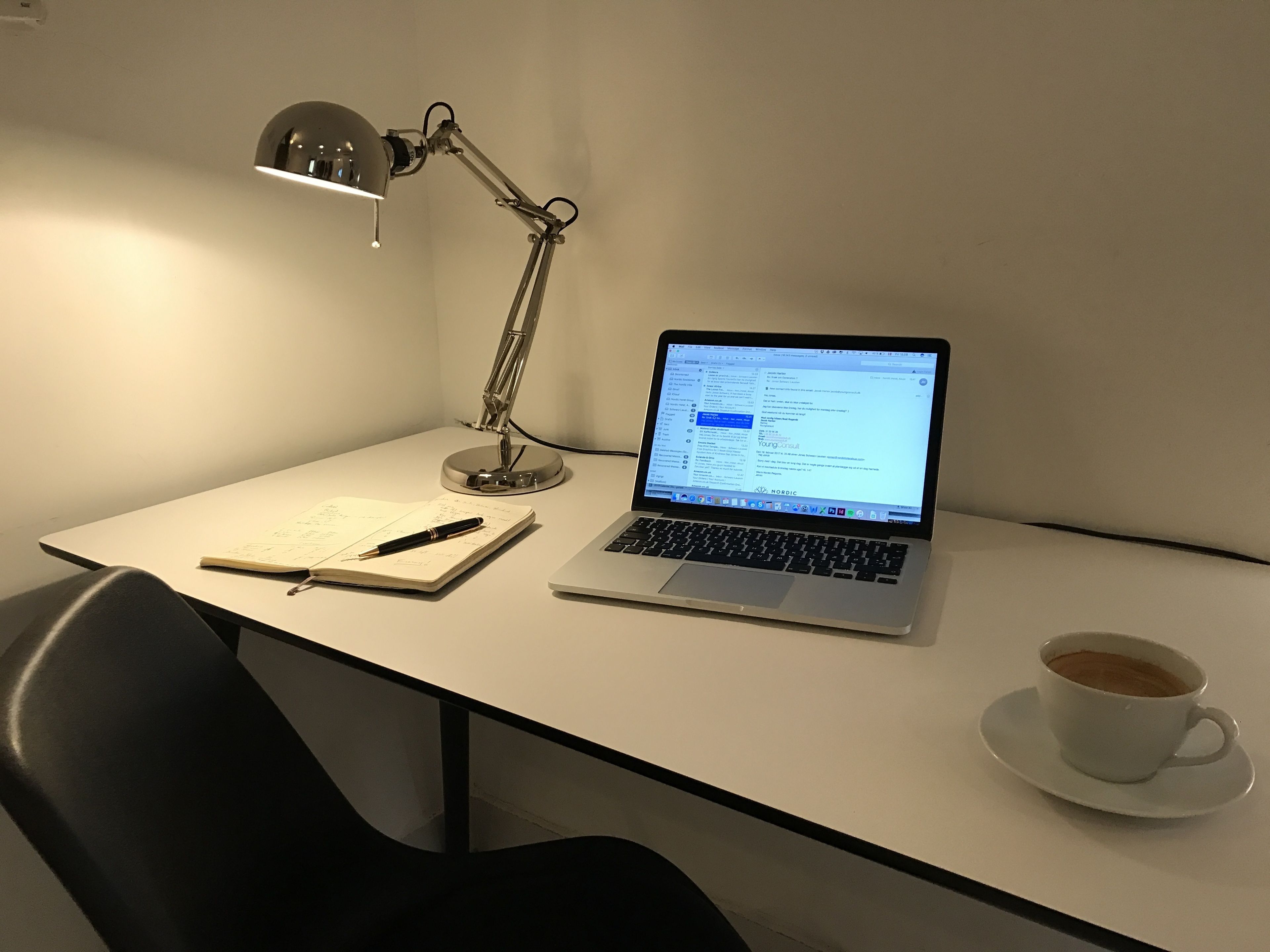 Een bureau met een laptop, een notitieboek, een pen en een kop koffie.