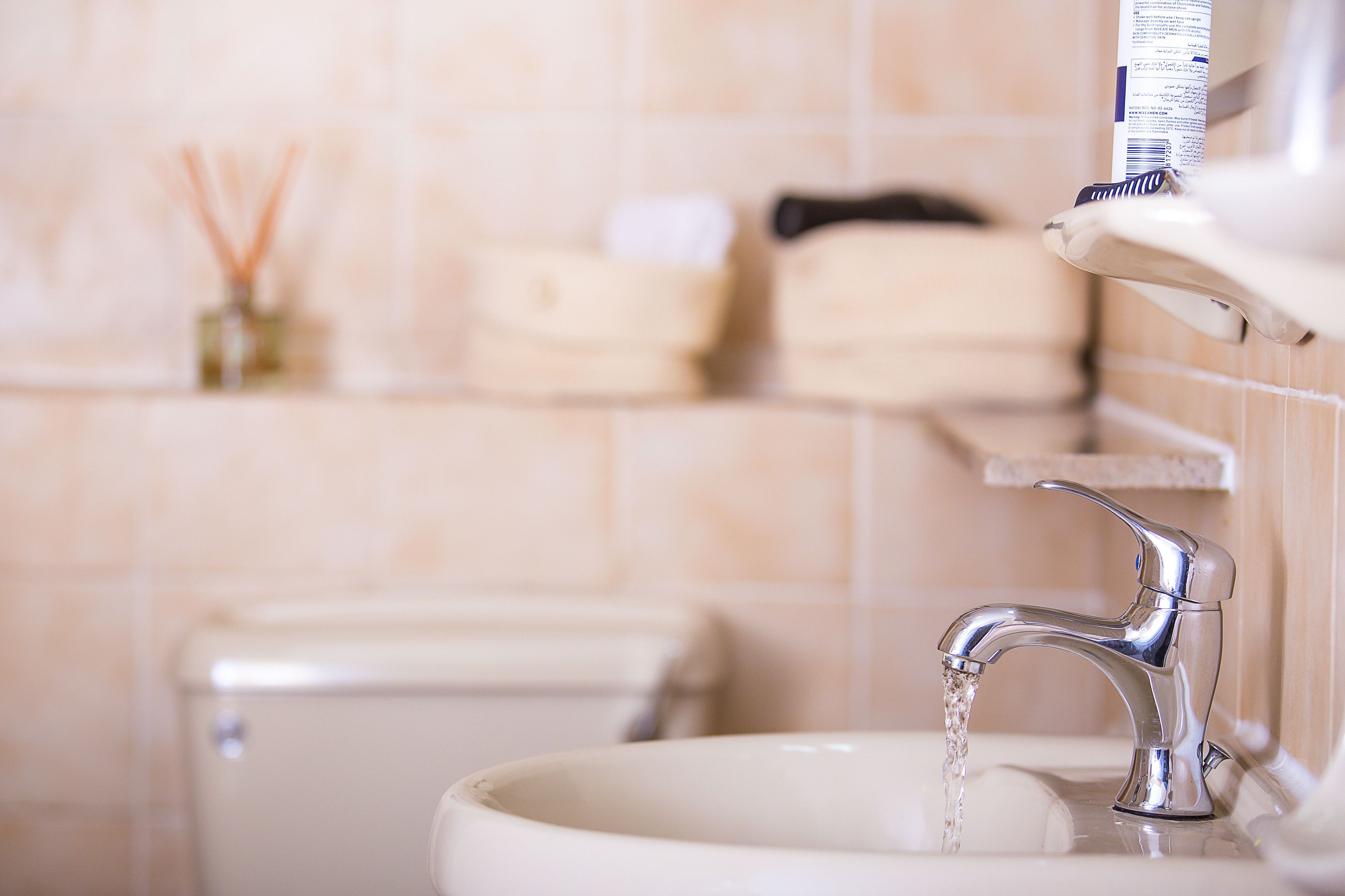 Ein Waschbecken mit fließendem Wasser, eine Toilette und ein Ablagefach mit Pflegeprodukten.