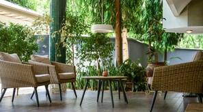 An outdoor seating area with wicker furniture, a table, and potted plants. - The Nordic Villa (Abuja)
