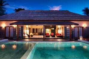 Una piscina al aire libre, sombrillas, sillones reclinables de piscina