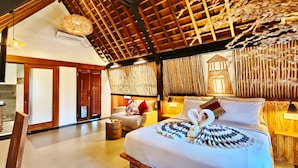 Quarto amplo com cama grande, teto de madeira e parede de bambu.