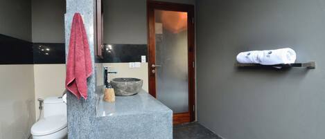 Et moderne badeværelse med bordplade i granit, et hvidt toilet, en stor vask og en håndklæderække.