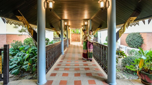 Un paseo techado con suelo a cuadros, columnas y barandillas decorativas.