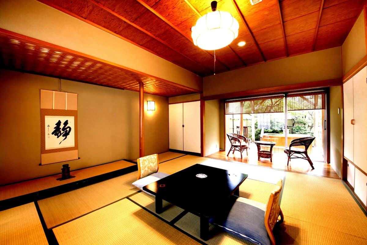 Une pièce de style japonais traditionnel, avec un sol recouvert de tatamis, une table basse et des portes coulissantes.
