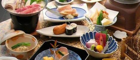 Variedad de platos japoneses, como sushi, sashimi y tempura, dispuestos sobre una mesa.