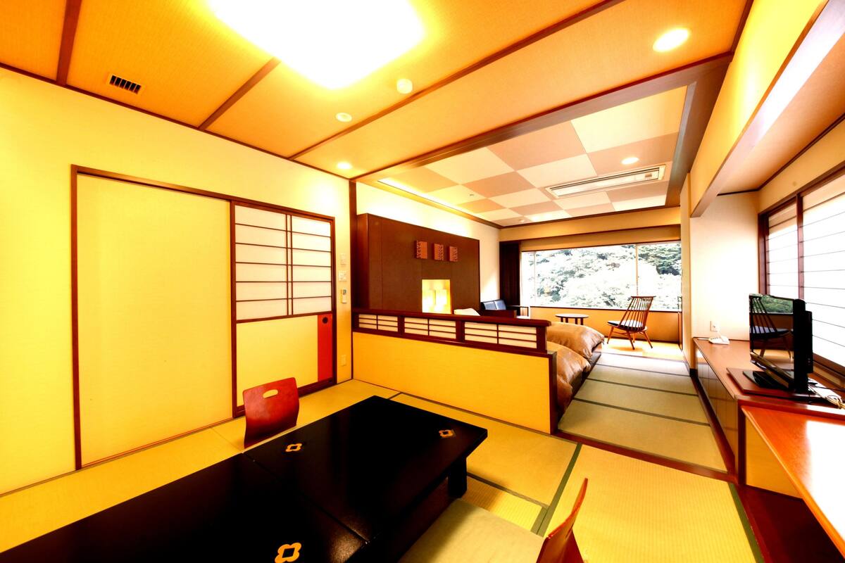 Une pièce de style japonais traditionnel, avec un sol recouvert de tatamis, une table basse, un canapé et un téléviseur.