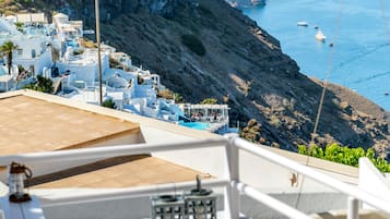 A deck with lounge chairs overlooking a coastal village with white buildings and cliffs.
