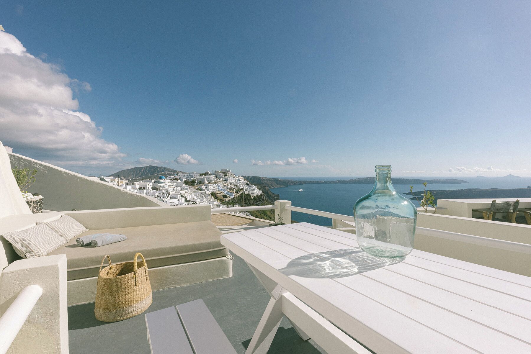 Un espacio exterior con asientos blancos y vistas despejadas de un pueblo costero y el mar.