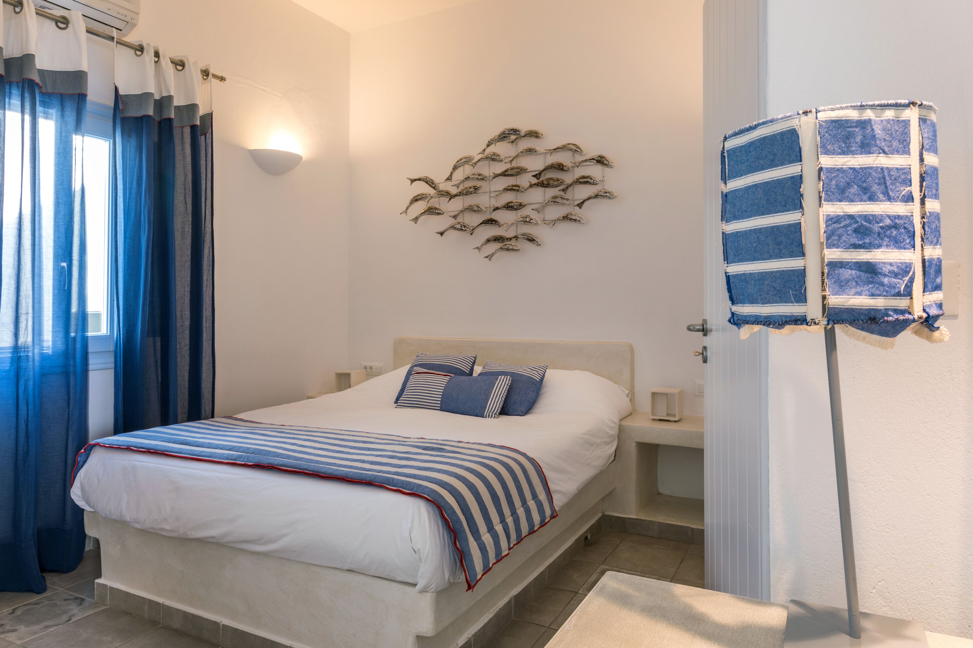 Un dormitorio con una cama, una lámpara de pared, un adorno mural y un perchero.