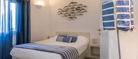 Un dormitorio con una cama, una lámpara de pared, un adorno mural y un perchero.
