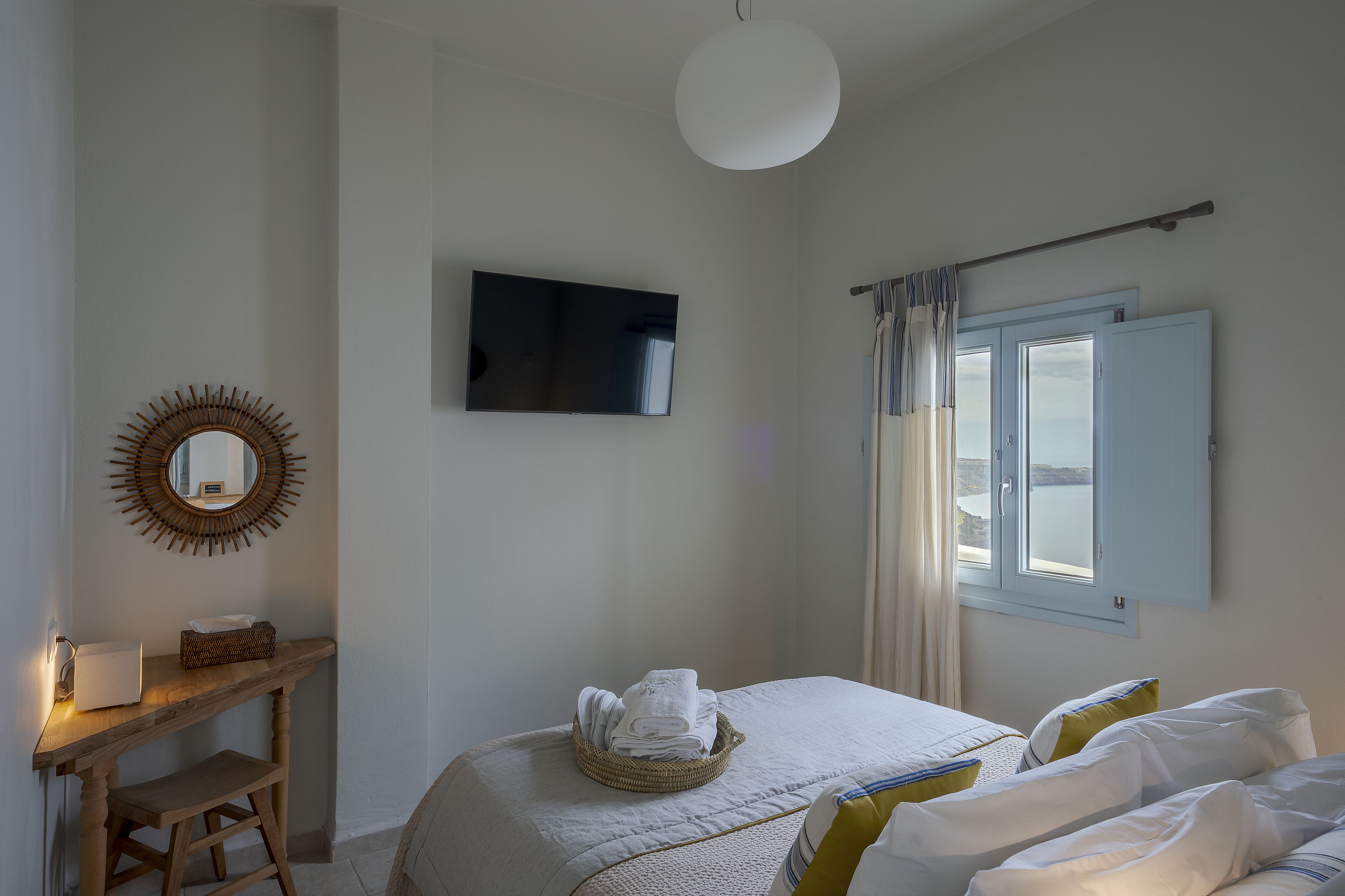 Un dormitorio con cama, una mesita de noche con lámpara, un televisor y una ventana con cortinas.