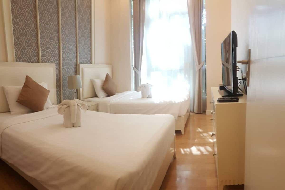 A hotel room with two beds, a television, and a wardrobe.