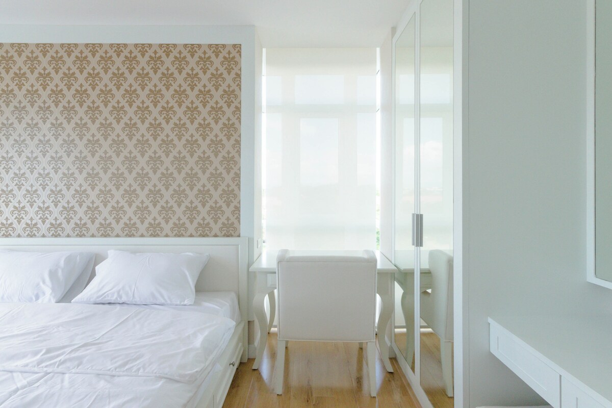 A bedroom with a bed, a chair, and a wardrobe.
