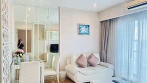 Una sala de estar moderna con un sofá blanco, una mesa de comedor de cristal y un televisor de pantalla plana.
