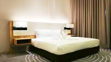A hotel room with a large bed, two bedside tables with lamps, a headboard, and a patterned carpet.