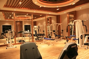 A gym with various exercise equipment, wooden flooring, and a mirrored wall.