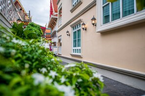 A narrow street with buildings on either side, featuring balconies and windows with external lighting. - The Orchid House 153 (Bangkok)
