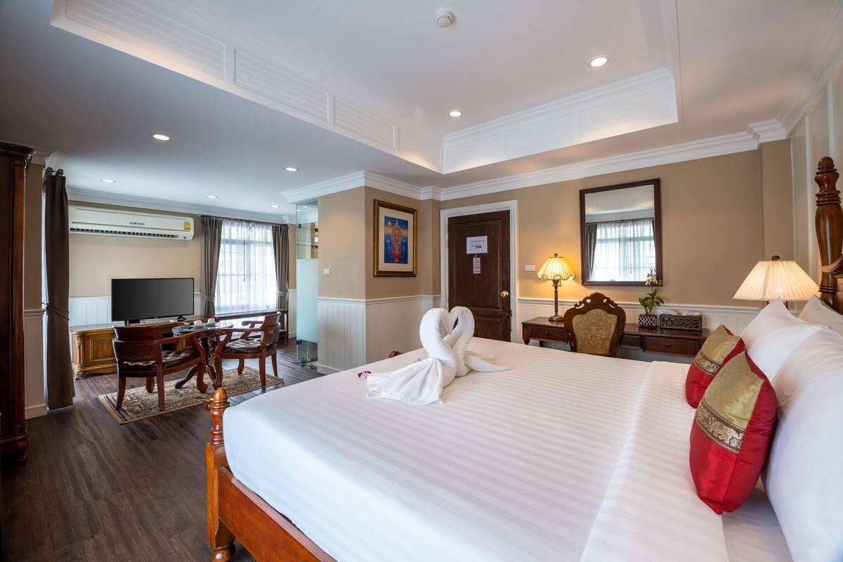 Une chambre d’hôtel avec un grand lit, un bureau avec une chaise, une télévision et une porte.