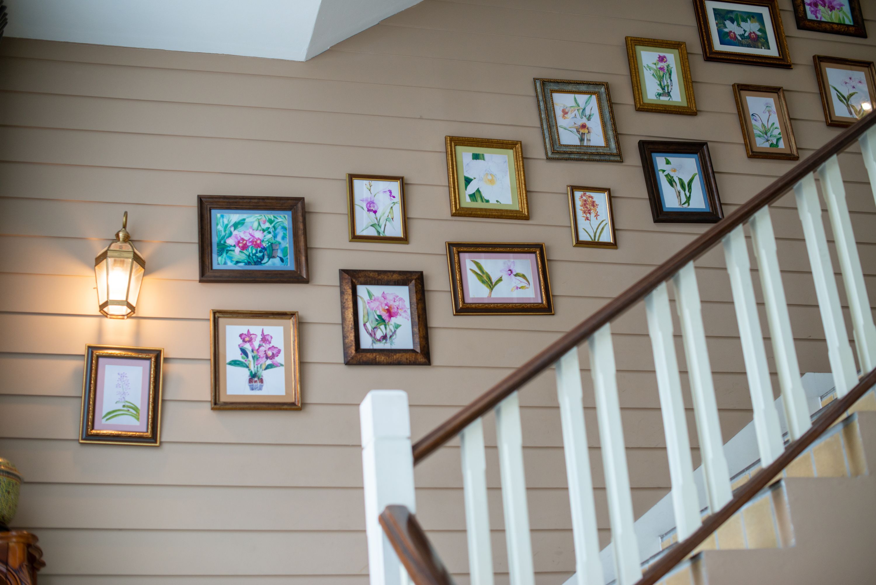 Una escalera con barandilla y pared decorada con cuadros de flores.