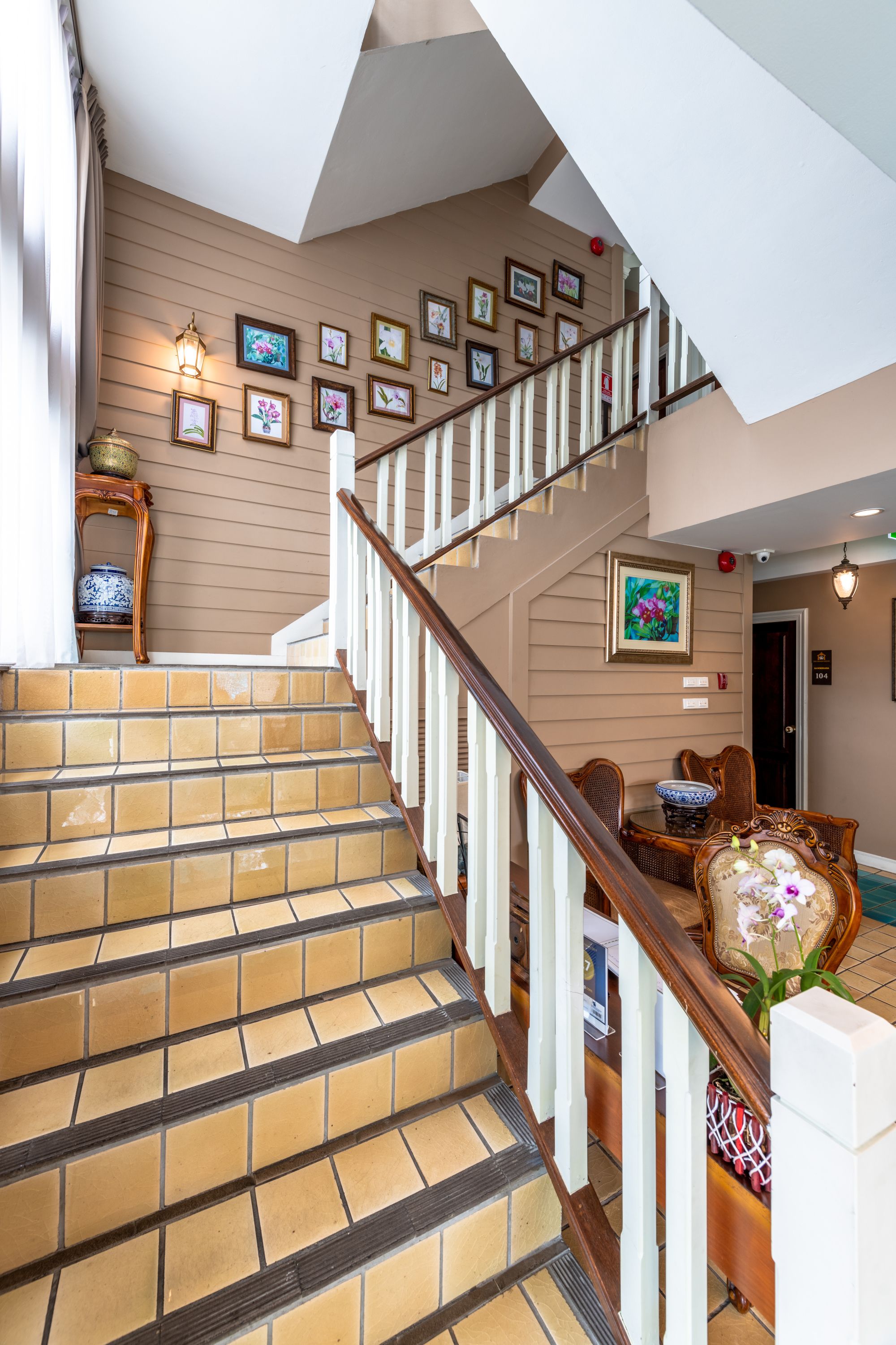 A staircase with a wooden railing, beige walls, and framed pictures on the wall.