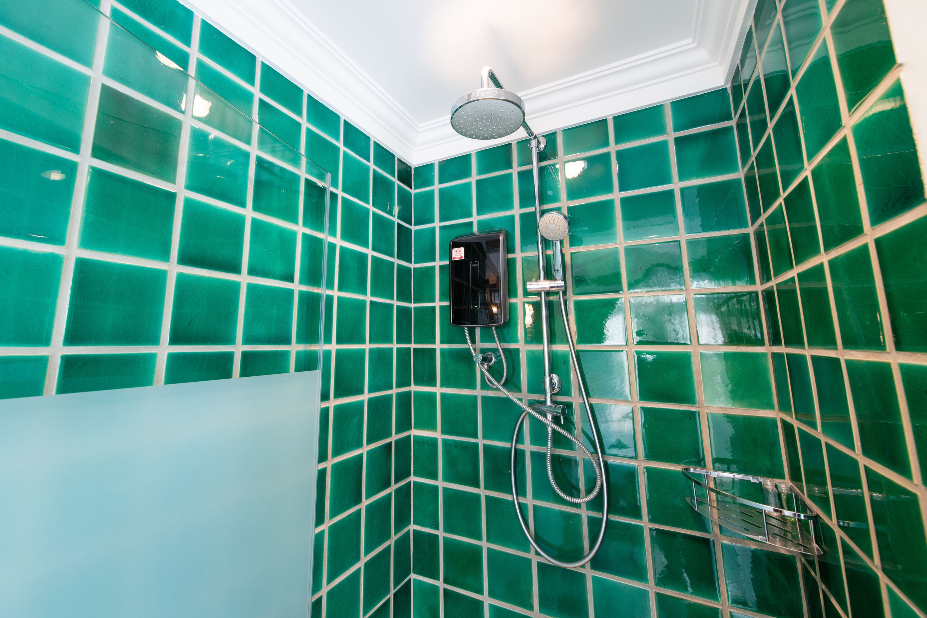 Un baño con paredes de azulejos verdes y una zona de ducha.