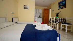 Una camera d'albergo con un letto, una scrivania, una sedia, un angolo cottura e un bagno.