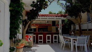 Una terrazza esterna con un'area bar, mobili bianchi e piante in vaso.