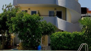 Un edificio a più piani con balconi, piscina e vegetazione circostante.