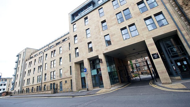 A multi-story building with a modern architectural design, featuring a prominent entrance with a glass door and a metal gate. - Citylivein Grove Street Edinburgh (Edinburgh)