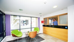 A reception area with a reception desk, two green chairs, a black and white checkered floor, and large windows with purple curtains. - Citylivein Grove Street Edinburgh (Edinburgh)