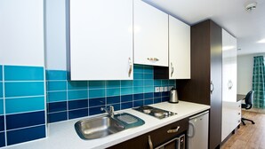 A modern kitchen with white cabinets, a stainless steel sink, and a built-in oven. - Citylivein Grove Street Edinburgh (Edinburgh)