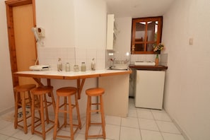 A compact kitchen with a wooden bar stool area, a refrigerator, and a window with a view.