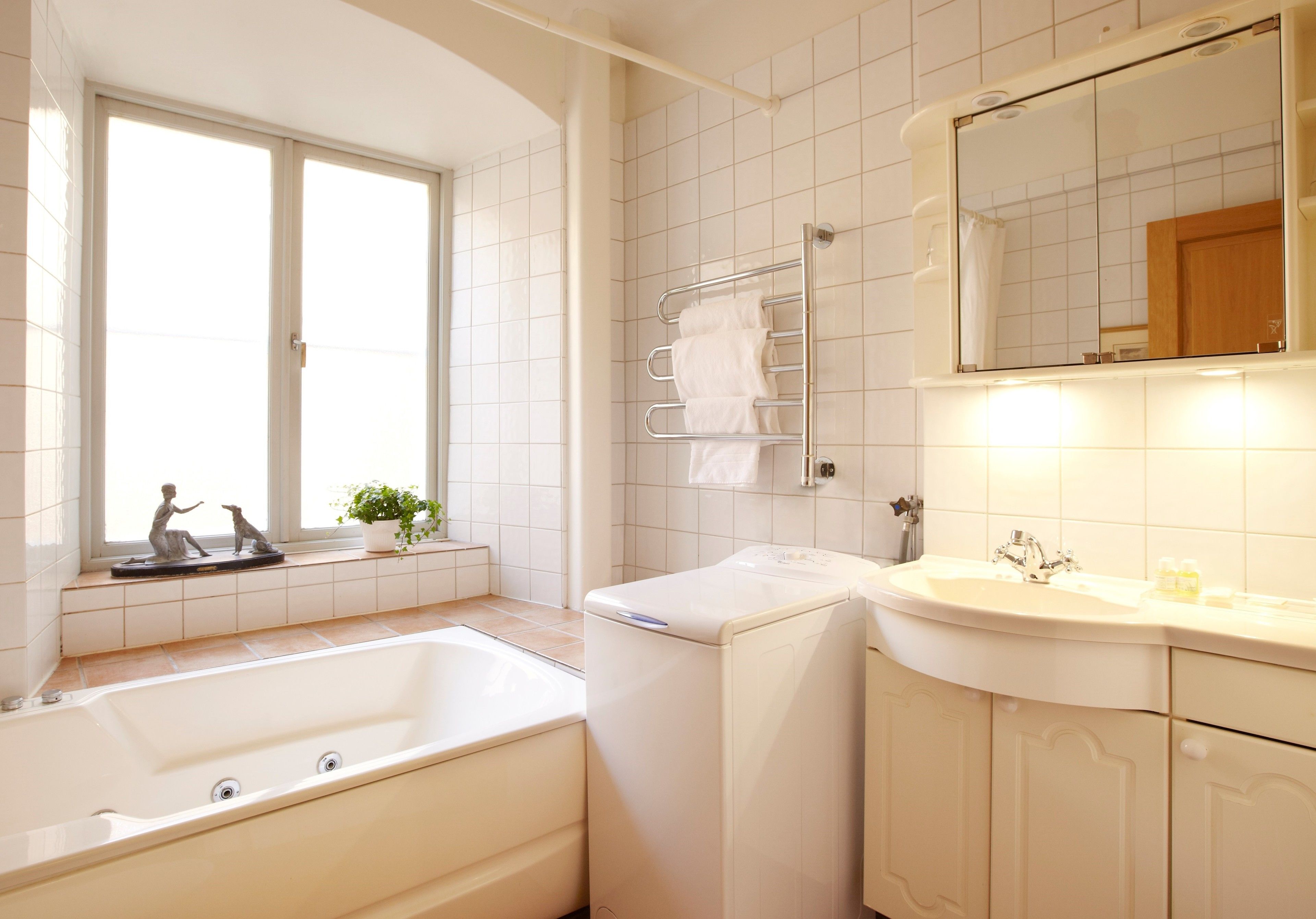 Un baño moderno con bañera, lavadora, lavamanos y espejo.