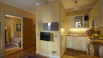 A compact kitchen with a built-in oven, a microwave, and a sink. There's a wooden dining table and a chair.