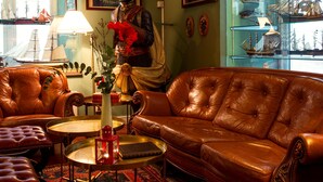 A room with a brown leather sofa, a round coffee table, and a red patterned rug.