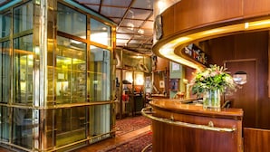 A reception area with a wooden counter, glass walls, and a red carpet.