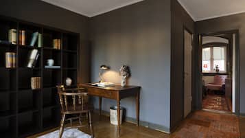 A study room with a wooden desk, a chair, a bookshelf, and a rug.