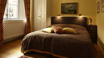 Ein Schlafzimmer mit einem Bett, einer Kandelaber, einem Gemälde, einem Kleiderschrank und einem gemusterten Teppich.